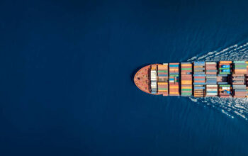 Aerial top down view of a large container cargo ship in motion over open ocean with copy space